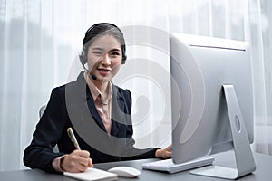 Enthusiastic asian call center with headset on her workplace portrait.