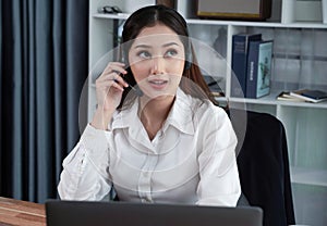 Enthusiastic asian call center with headset and microphone working on her laptop