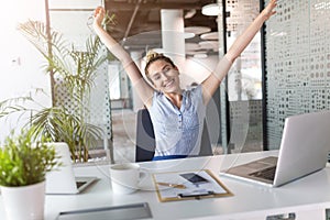 Enthusiastic businesswoman with arms raised in office