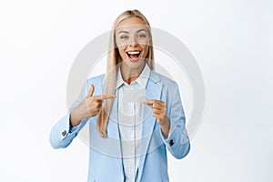 Enthusiastic businesswoman pointing and showing credit card, concept of bank advertisement, standing over white