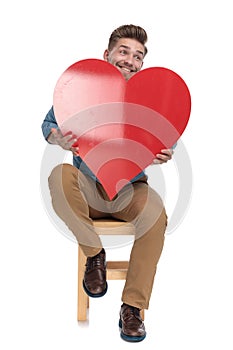 Enthusiastic casual man holding big red heart