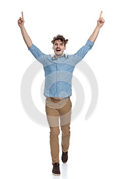 Enthusiastic casual man pointing fingers in the air and celebrating