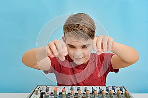 An enthusiastic child is about to tune a music mixing console