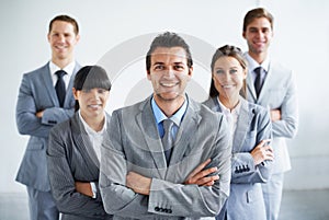 Enthusiastic and confident. Portrait of a confident business manager crossing his arms and standing with his team.