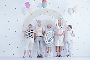 Enthusiastic elderly people with colorful balloons celebrating f