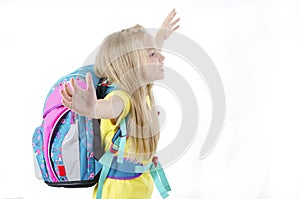 Enthusiastic elementary school girl posing with arms raised up, victorious. Side view.