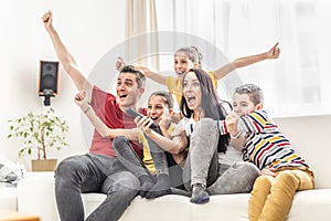 Enthusiastic family of five cheers at home watching sports on TV