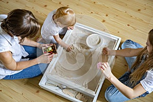 Enthusiastic family playing home kinetic sandbox use wooden ecological toys enjoying leisure