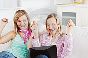 Enthusiastic friends with arms up and a laptop