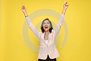 Enthusiastic girl in pink suit holding arms above head