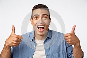 Enthusiastic good-looking young happy guy, showing thumbs-up, encourage someone, praise friend did good job, smiling nod