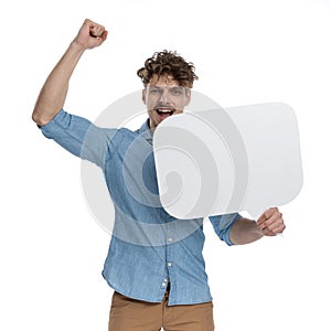 Enthusiastic guy holding speech bubble and celebrating victory