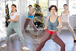 Enthusiastic Hispanic woman leading dance fitness class during Christmas season