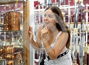 Enthusiastic young girl looking at artisanal copper utensils in souvenir shop