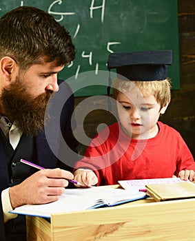 Enthusiastic kid studying with teacher. Father checking homework, helps to boy, son. Teacher in formal wear and pupil in