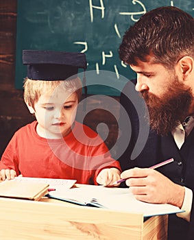 Enthusiastic kid studying with teacher. Father checking homework, helps to boy, son. Teacher in formal wear and pupil in