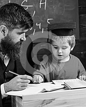 Enthusiastic kid studying with teacher. Father checking homework, helps to boy, son. Teacher in formal wear and pupil in