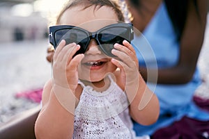 Enthusiastic little girl holding big sunglasses with her hands