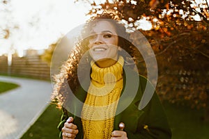 enthusiastic look and beautiful white-toothed smile on the face of the curly brunette in a bright yellow sweater and