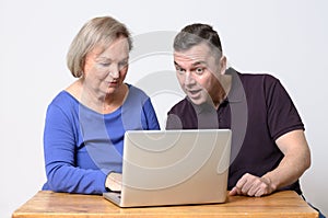 Enthusiastic man looking at laptop with woman