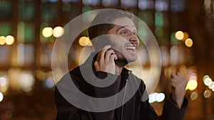 Enthusiastic man speaking mobile phone outdoors. Happy guy expressing delight.