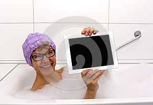 Enthusiastic mature woman in bathtub with tablet computers