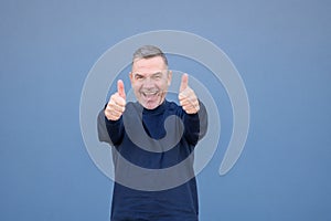 Enthusiastic middle aged man giving a double thumbs up gesture with a beaming smile