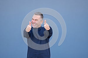 Enthusiastic middle aged man giving a double thumbs up gesture with a beaming smile