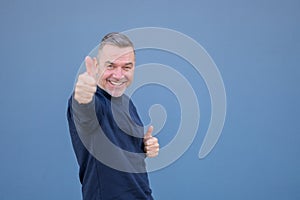 Enthusiastic middle aged man giving a thumbs up gesture with a beaming smile