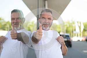 Enthusiastic smiling senior man giving a thumbs up of success