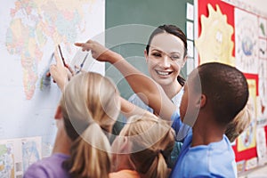 Enthusiastic about teaching. An excited class pointing at a world map with their geography teacher.