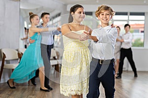 Enthusiastic teenagers performing waltz during group dance lesson