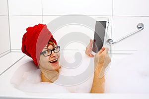 Enthusiastic woman in bathtub with tablet computers