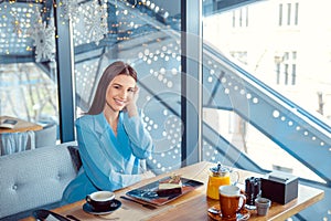 Enthusiastic Woman chilling in cozy cafe adjusting hair