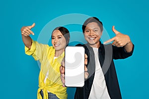 Enthusiastic woman and man pointing with excitement to a smartphone with a blank screen