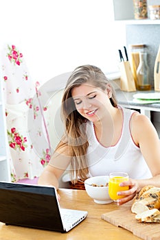 Enthusiastic woman using laptop during breakfast