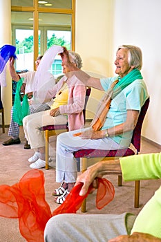 Enthusiastic women doing exercises in chairs.