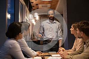 Enthusiastic young african guy present problem solution to diverse colleagues