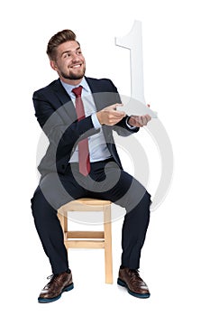 Enthusiastic young businessman holding number one sign