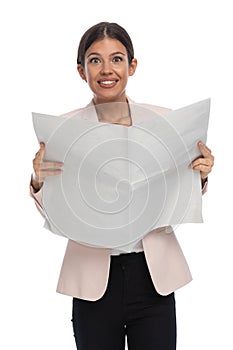 Enthusiastic young businesswoman smiling and reading newspaper