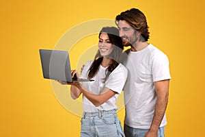 Enthusiastic young couple collaboratively using a laptop computer, showing teamwork