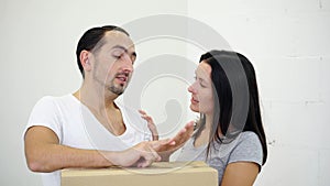 Enthusiastic young couple standing leaning to cardboard box in a new apartment, discussing the layout of the house.