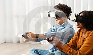 Enthusiastic young couple with VR headsets engaged in an interactive video game