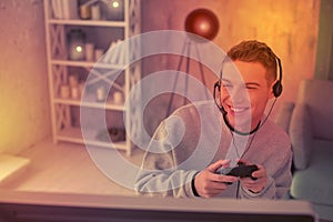 Enthusiastic young fellow using gamepad for videogame