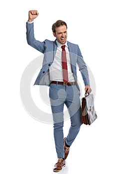 Enthusiastic young guy holding fist up and celebrating victory