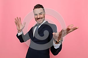 Enthusiastic young guy in suit holding hands in the air