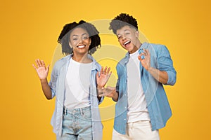 Enthusiastic young woman and man with bright smiles waving hello or goodbye, the man