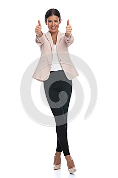 Enthusiastic young woman in pink jacket making thumbs up gesture