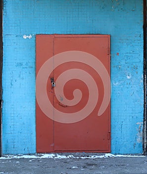 Entrance brown metal door in blue wall