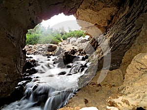 Entrance of a Cave River with a small waterfall into an underground cave